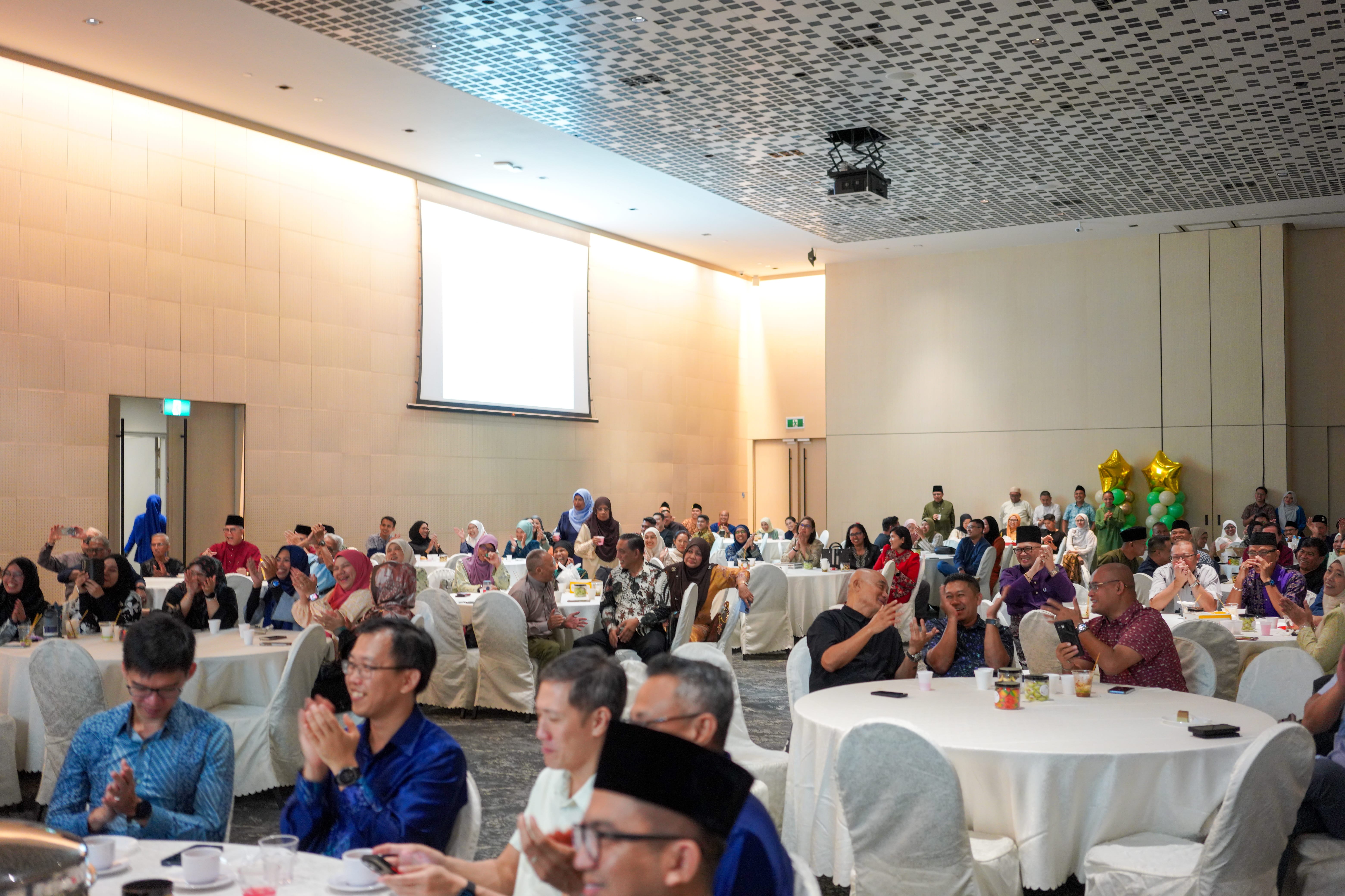 Guests across the banquet hall applauding and watching the entertainment programme during the celebration.